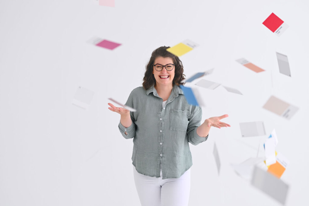 Evi lacht, um sie herum fliegen bunte Farbkarten