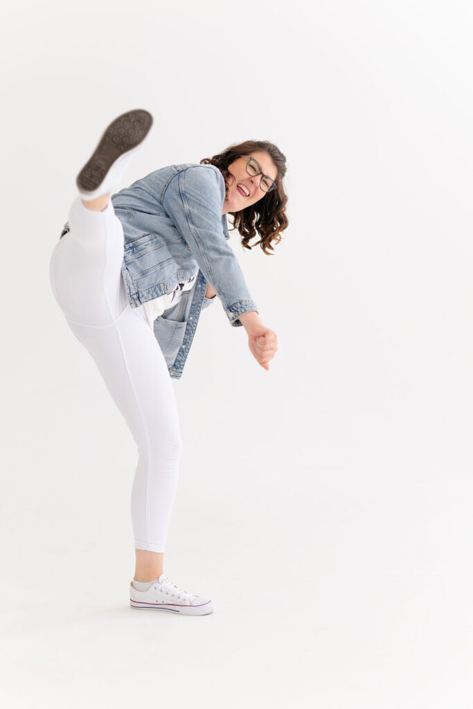 Evi in Jeansjacke kickt fröhlich ein Bein in die Luft