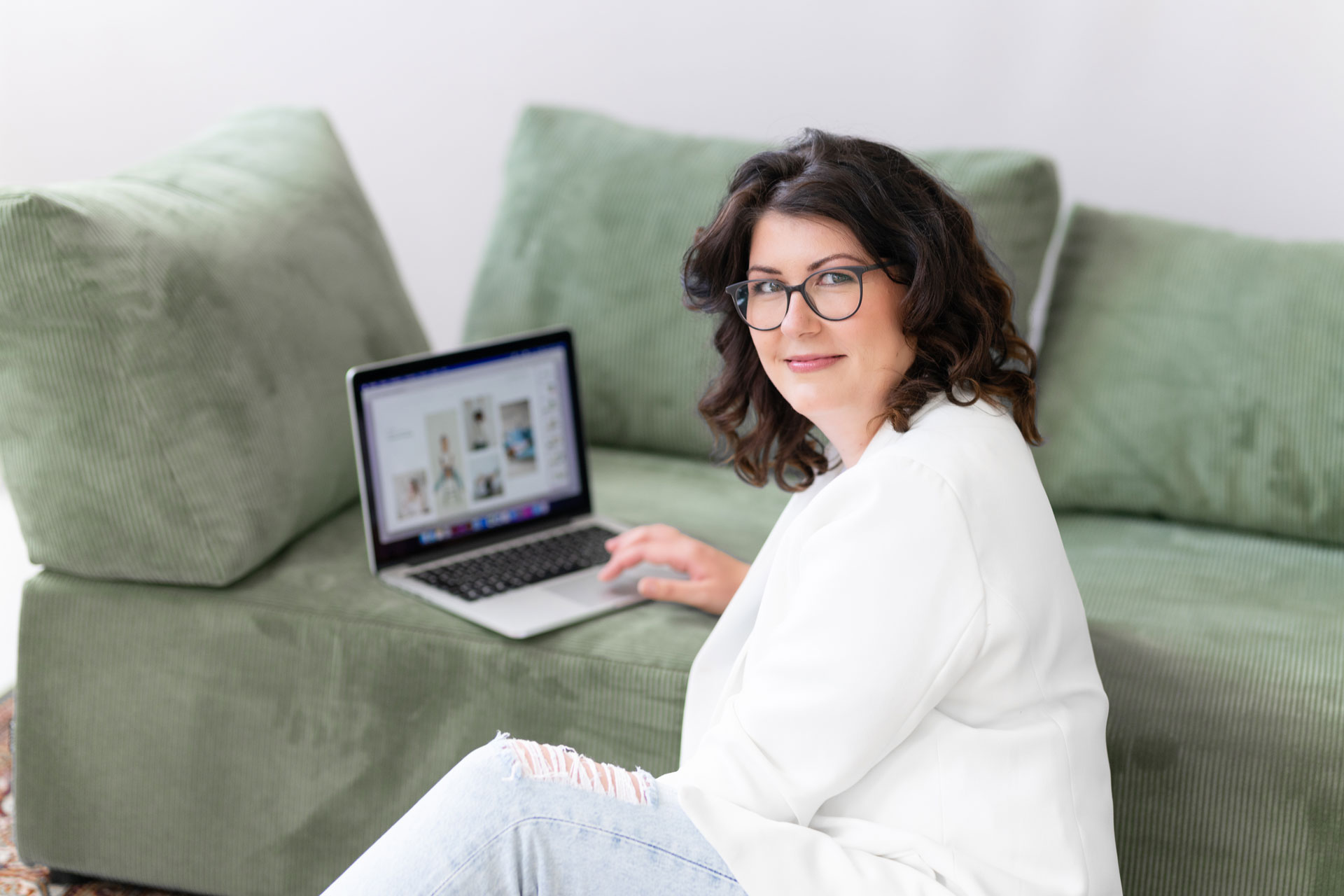 Evi arbeitet entspannt am Laptop auf dem grünen Sofa
