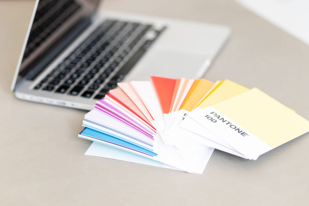 Farbfächer mit Pantone-Mustern neben einem Laptop