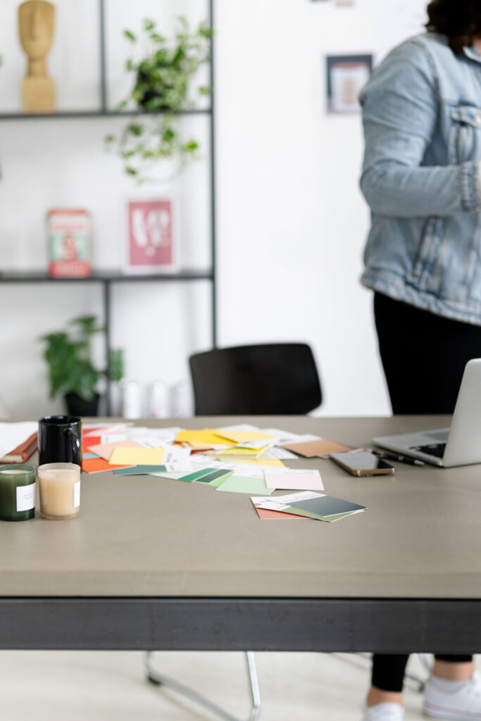 Arbeitstisch mit Farbkarten, Druckmustern und Laptop